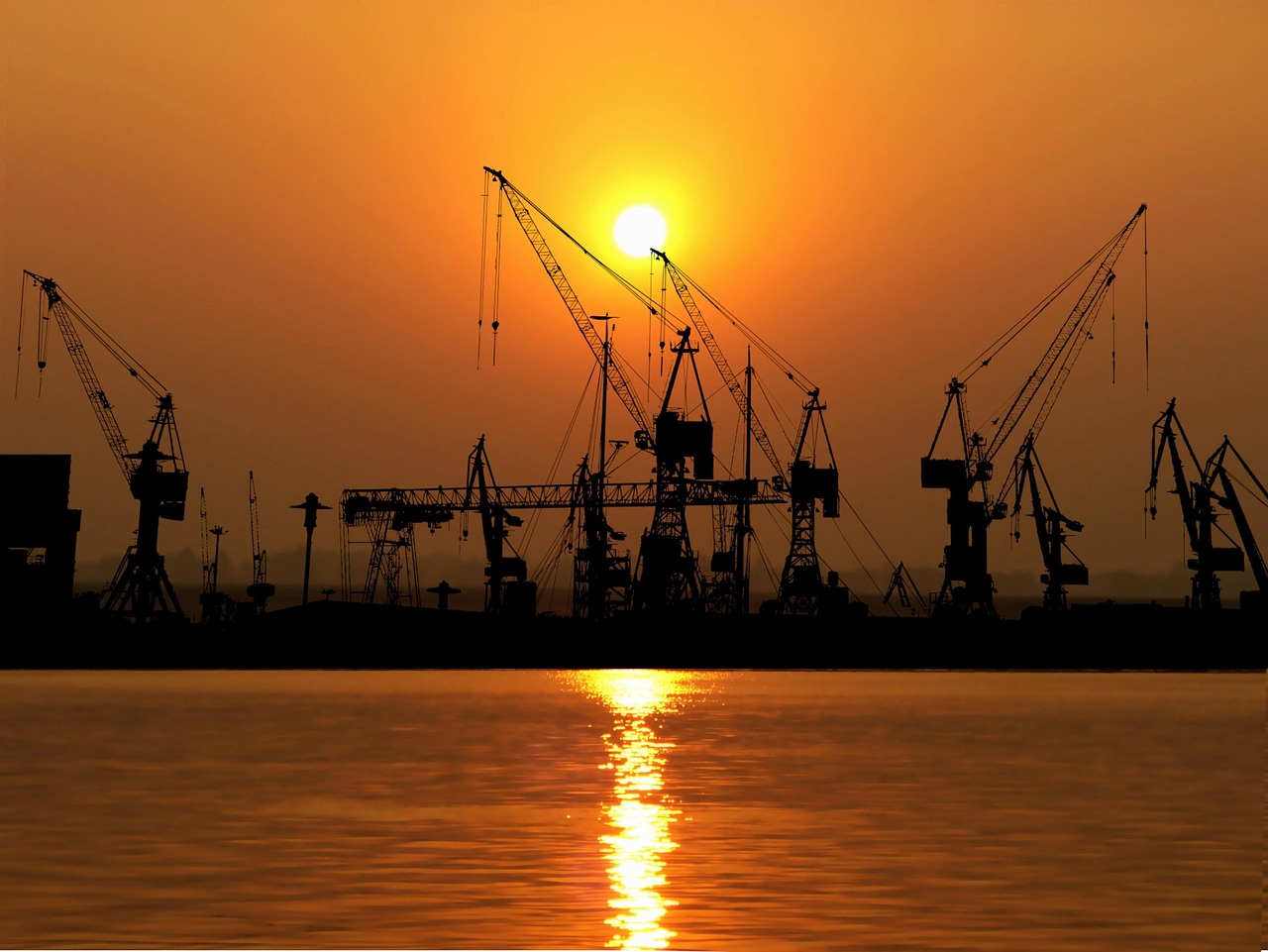 Port cranes silhouetted against the sunset